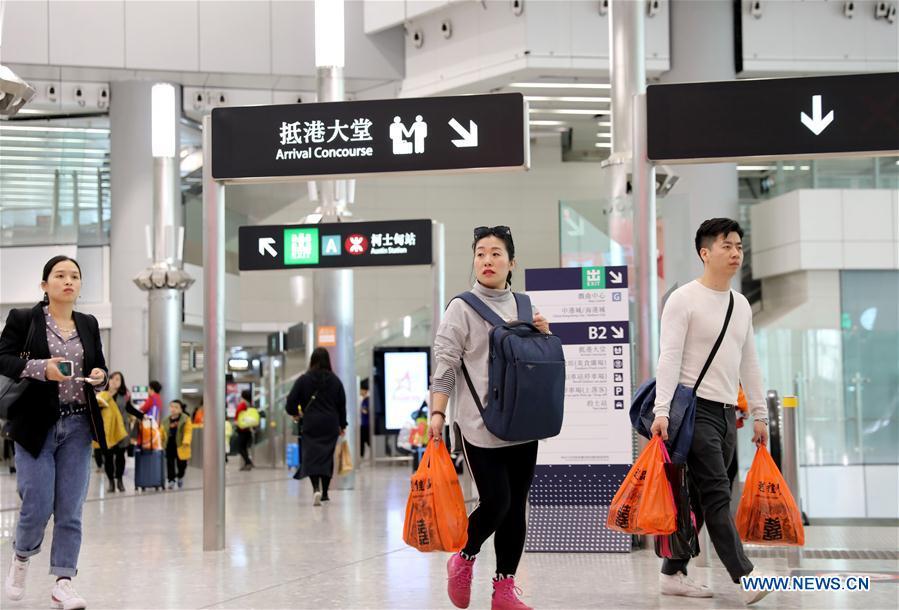 Passengers walk at the West Kowloon railway station in Hong Kong, south China, Jan. 25, 2019. To better serve the passengers using the automotive ticket machines, blue signs are installed and staff members in orange are dispatched to offer help at the West Kowloon railway station in Hong Kong. (Xinhua/Wu Xiaochu)