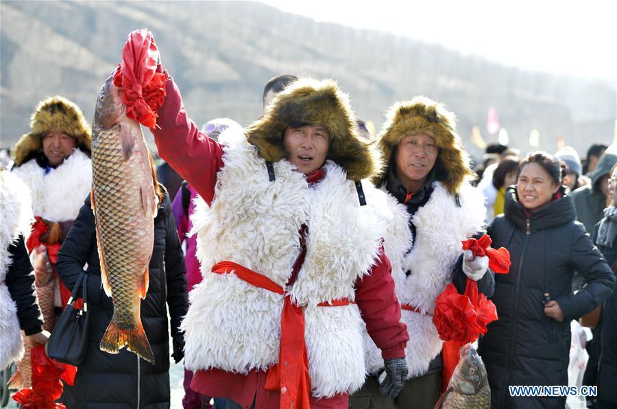 An Inheritor of Chagan Lake winter fishing heritage shows a fish just caught in Qianyaozi Reservoir in Hohhot, capital of north China\'s Inner Mongolia Autonomous Region, Jan. 26, 2019. A two-day winter fishing tourism festival opened here on Saturday, during which 18 inheritors of Chagan Lake winter fishing showed visitors traditional ways of fishing. Winter fishing on ice-covered Chagan Lake dates back to the Liao and Jin dynasties from 10th century to the 13th century in China and was listed into the national intangible cultural heritage in 2008. (Xinhua/Wang Zheng)