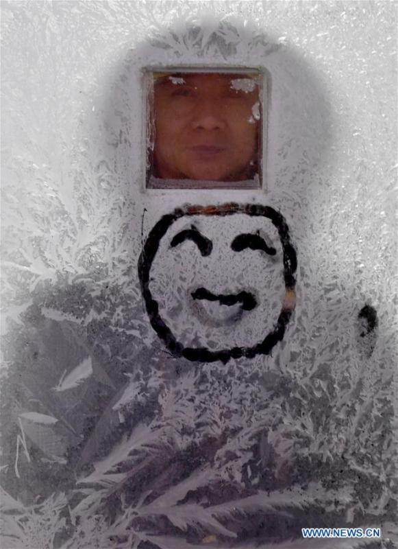 A railway staff looks through a frosted window on train No. 6245 which travels from Qiqihar to Gulian in northeast China\'s Heilongjiang Province, early on Jan. 23, 2019. Train No. 6245 is one of China\'s most economical railway trains which are bound for remote destinations. During China\'s Spring Festival travel season, these \