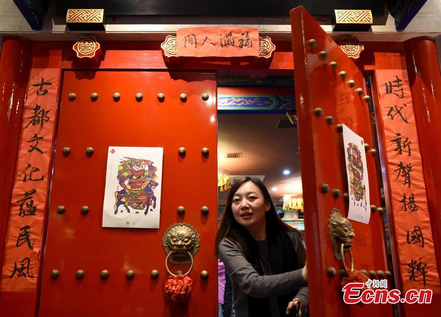 A woman walks out of the Lao She Tea house in Beijing, where a Spring Festival paintings exhibition is being held, Jan. 27, 2019. The exhibition, organized by the Ministry of Culture and Tourism and Prince Gong\'s Mansion, presented representative traditional paintings of the Lunar New Year from across the country, and will run from Jan. 28 to Feb. 28. (Photo: China News Service/Hou Yu)