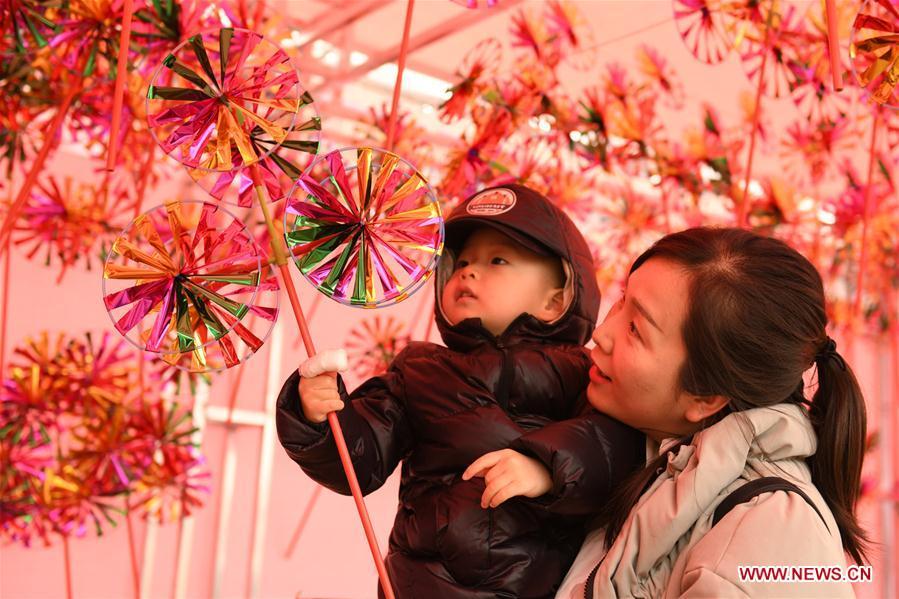 A child accompanied by his mother selects toy windmill at a street market in Zhengding County of Shijiazhuang, north China\'s Hebei Province, Jan. 27, 2019. People across China are busy preparing for the upcoming Chinese Lunar New Year, which falls on Feb. 5 this year. (Xinhua/Chen Qibao)