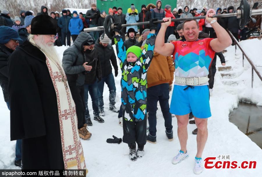 A Russian Orthodox clergeman (L) and bodybuilder Yuri Golubev (R front) before a world record attempt by Andrei Lobkov (not in picture) for the most consecutive bench presses in 1 minute while standing in an ice hole, in the frozen Moskva River in north-west Moscow; the record attempt is dedicated to John the Baptist.  (Photo/Sipaphoto.com)