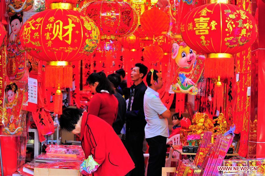 People select lunar new year decorations at a street market in Lingshui Li Autonomous County, south China\'s Hainan Province, Jan. 26, 2019. People across China are busy preparing for the upcoming Chinese Lunar New Year, which falls on Feb. 5 this year. (Xinhua/Liu Shuting)