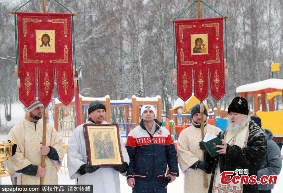 Russian Orthodox believers and bodybuilding and fitness trainer Andrei Lobkov (C) listen to prayers before a world record attempt by Lobkov for the most consecutive bench presses in 1 minute while standing in an ice hole, in the frozen Moskva River in north-west Moscow; the barbell is half the weight of Lobkov; Lobkov dedicated his record attempt to John the Baptist. (Photo/Sipaphoto.com)