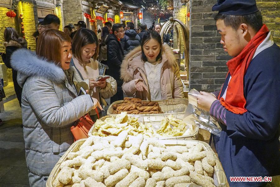People select traditional snacks on a food and culture street in Tangshan, north China\'s Hebei Province, Jan. 26, 2019. People across China are busy preparing for the upcoming Chinese Lunar New Year, which falls on Feb. 5 this year. (Xinhua/Liu Mancang)