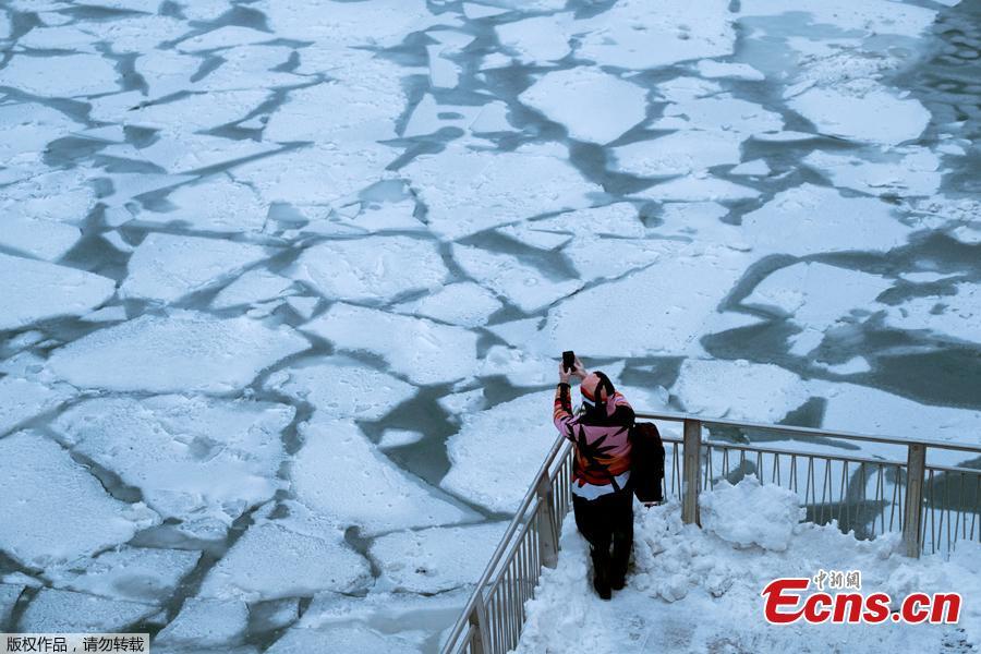 A pedestrian stops to take a photo by Chicago River, as bitter cold phenomenon called the polar vortex has descended on much of the central and eastern United States, in Chicago, Illinois, U.S., January 29, 2019.  REUTERS/Pinar Istek