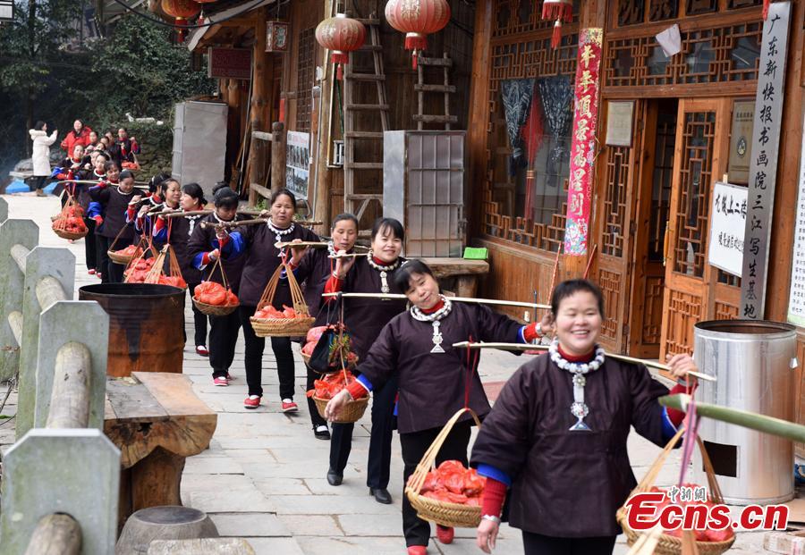 Nearly 200 women of the Dong ethnic group attend a group activity that shows the traditional custom of outmarried women going back to the home of their parents, often donning grand costumes and carrying gifts, in Pingyan Village, Sanjiang Dong Autonomous County, Guangxi Zhuang Autonomous Region, Feb. 1, 2019. The custom has become a draw that attracts tourists. (Photo: China News Service/Gong Pukang)