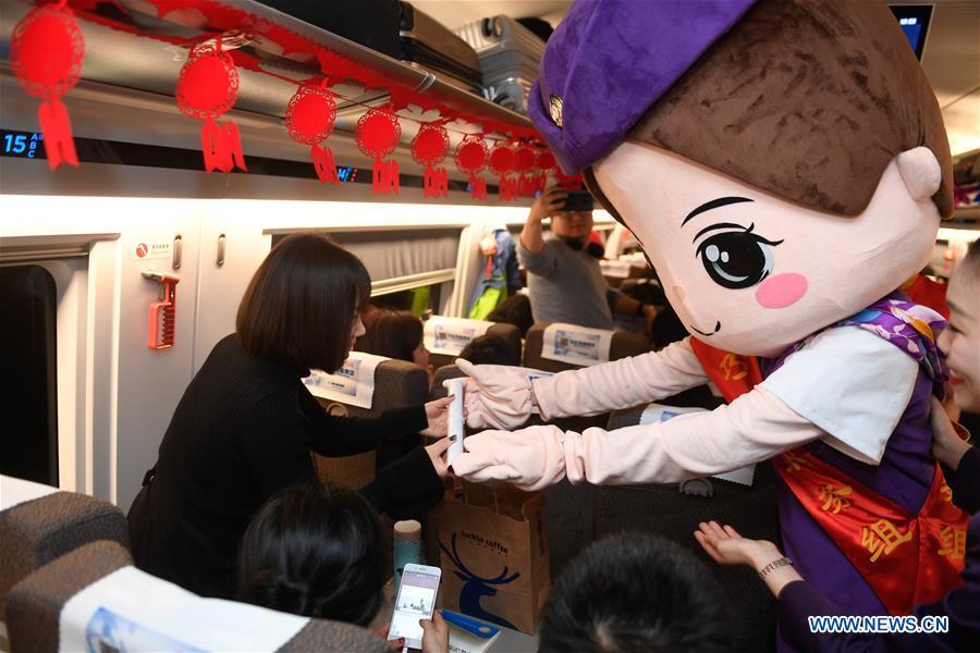 An attendant offers gifts to passengers aboard a bullet train from Hangzhou of east China\'s Zhejiang Province to Huangshan of east China\'s Anhui Province, on Feb. 2, 2019. Staff members aboard the train staged a performance Saturday to extend greetings to the passengers, ahead of the Spring Festival, or the Chinese Lunar New Year, which falls on Feb. 5 this year. (Xinhua/Huang Zongzhi)