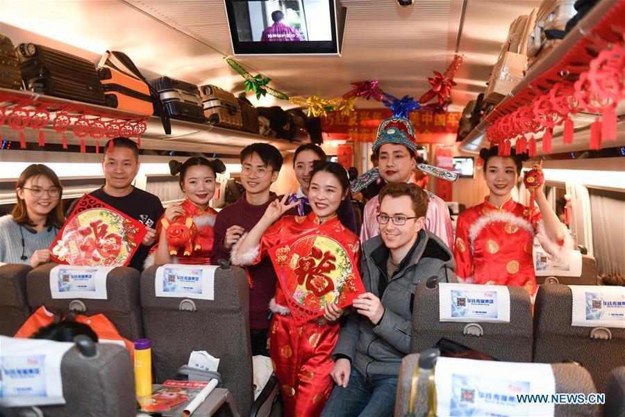 Attendants in costumes pose for photos with passengers aboard a bullet train from Hangzhou of east China\'s Zhejiang Province to Huangshan of east China\'s Anhui Province, on Feb. 2, 2019. Staff members aboard the train staged a performance Saturday to extend greetings to the passengers, ahead of the Spring Festival, or the Chinese Lunar New Year, which falls on Feb. 5 this year. (Xinhua/Huang Zongzhi)