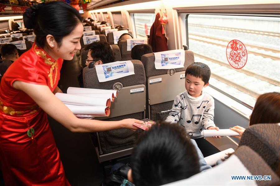 An attendant offers gifts to passengers aboard a bullet train from Hangzhou of east China\'s Zhejiang Province to Huangshan of east China\'s Anhui Province, on Feb. 2, 2019. Staff members aboard the train staged a performance Saturday to extend greetings to the passengers, ahead of the Spring Festival, or the Chinese Lunar New Year, which falls on Feb. 5 this year. (Xinhua/Huang Zongzhi)