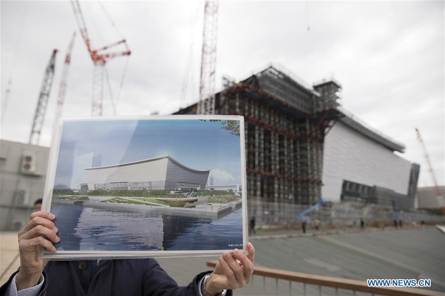 A staff member shows a design sketch of Ariake Arena, one of the Tokyo 2020 Olympic Games venues, at Ariake Arena construction site in Tokyo, Japan, on Feb. 12, 2019. This venue for volleyball games has been finished 51% construction works till the end of last month. (Xinhua/Du Xiaoyi)