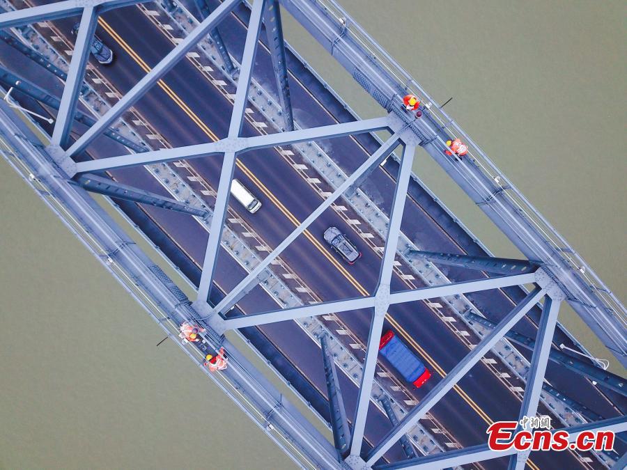 Technicians conduct a routine safety check on the Jiujiang Yangtze River Bridge, a major connection of the Beijing-Kowloon Railway in Jiujiang City, East China\'s Jiangxi Province during the travel peak of the Spring Festival. Despite the wind and vibration caused by the passing trains, they continued working in baskets hung under the bridge\'s girder, about 20 meters above the rolling Yangtze River. (Photo: China News Service/Ding Bo)