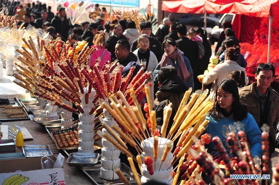 Tourists walk past booths selling tanghulu, a traditional Chinese snack of candied fruit, during an activity to greet the upcoming Lantern Festival in Lihua Village of Renqiu, north China\'s Hebei Province, Feb. 17, 2019. The traditional Chinese Lantern Festival falls on Feb. 19 this year. (Xinhua/Mu Yu)