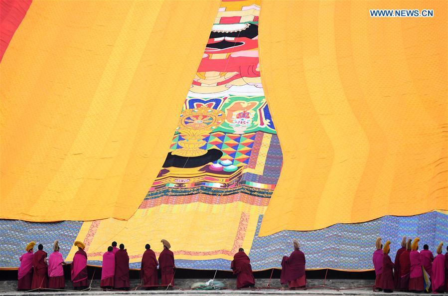 <?php echo strip_tags(addslashes(Lamas of the Labrang Monastery uncover the large yellow curtain on a huge thangka scroll painting bearing the image of the Buddha during the annual 