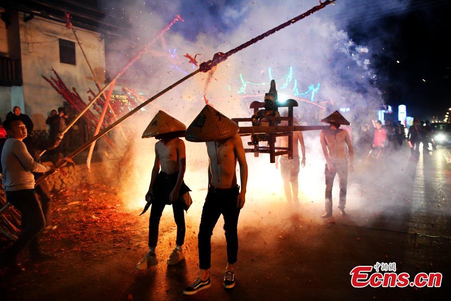 Shirtless men carrying the statue of a local deity perform amid firecrackers and sparklers during a folk festival in Yanfeng Village in Quanzhou City, East China\'s Fujian Province, Feb. 18, 2019. The tradition formed in the Ming Dynasty (1368-1644) is part of Lantern Festival celebrations on the 15th day of the first lunar month, or Feb. 19 this year. (Photo: China News Service/Wang Dongming)