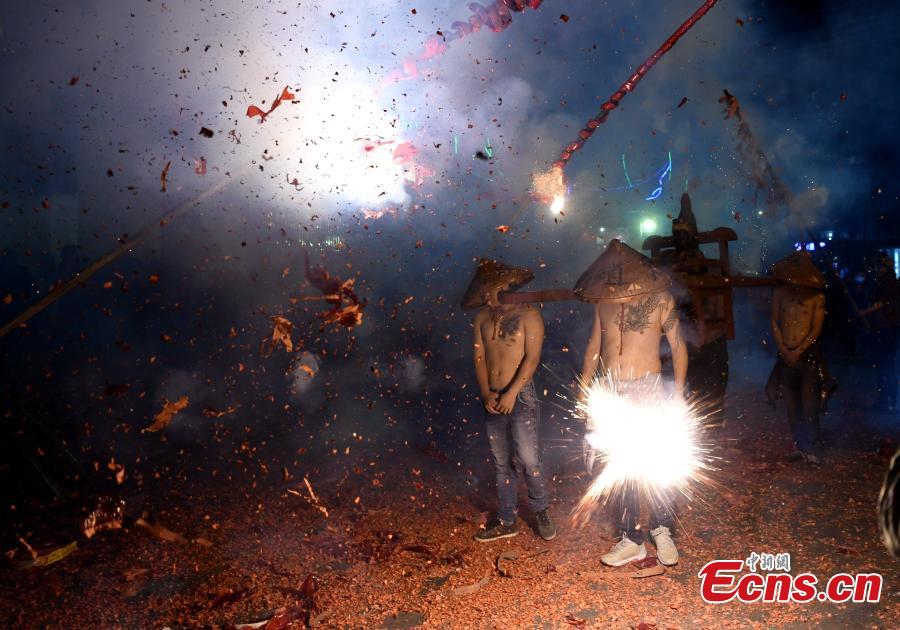 Shirtless men carrying the statue of a local deity perform amid firecrackers and sparklers during a folk festival in Yanfeng Village in Quanzhou City, East China\'s Fujian Province, Feb. 18, 2019. The tradition formed in the Ming Dynasty (1368-1644) is part of Lantern Festival celebrations on the 15th day of the first lunar month, or Feb. 19 this year. (Photo: China News Service/Wang Dongming)