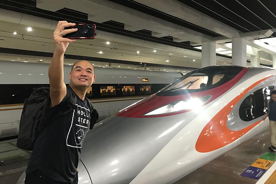 A passenger takes a selfie in front of a Vibrant Express train at Guangzhou South Station, South China\'s Guangdong province, after exiting the Vibrant Express train following its first run from Hong Kong to Guangzhou, Sept. 23, 2018. (Photo/China Daily)