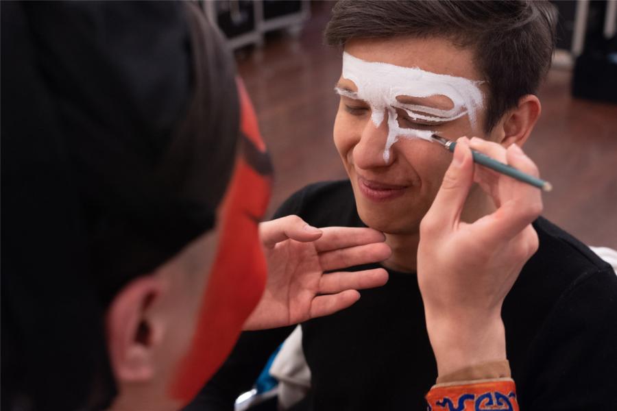 A performer puts makeup on the face of an overseas student. (Photo/chinadaily.com.cn)