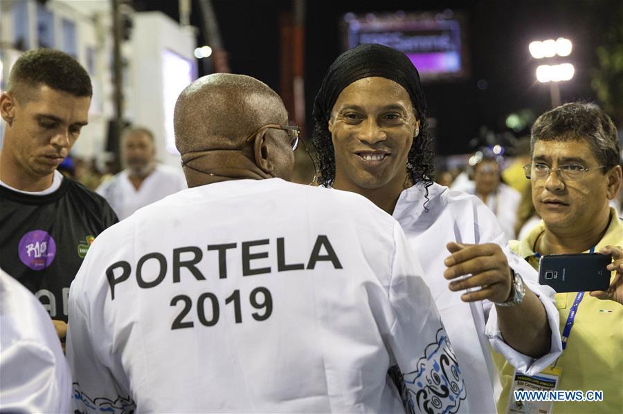 <?php echo strip_tags(addslashes(Brazil's former football player Ronaldinho (2nd R) hugs a member of samba school 