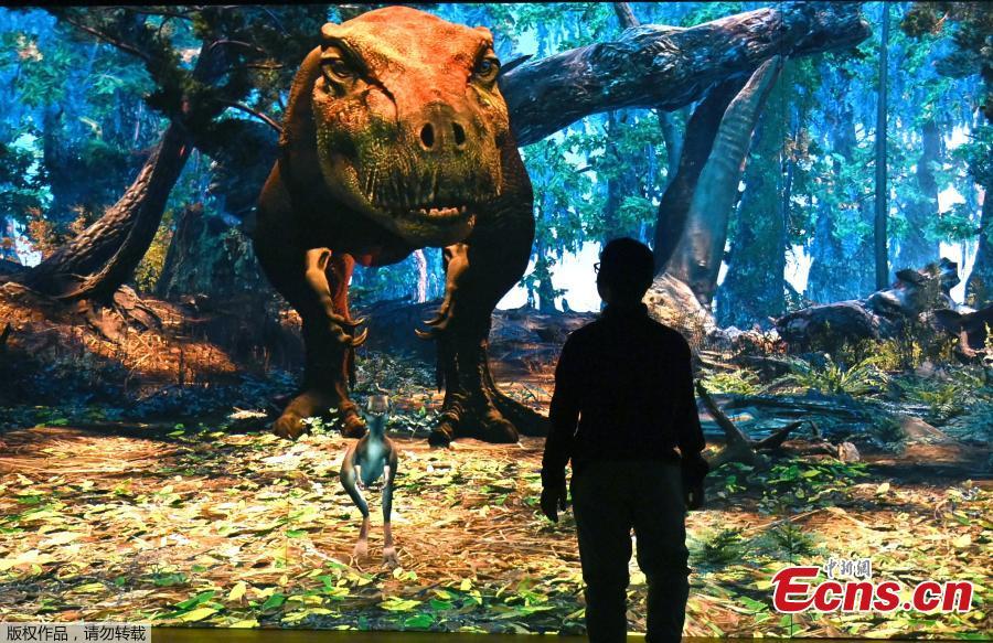 <?php echo strip_tags(addslashes(A man plays with an interactive screen featuring a Tyrannosaurus rex, during media preview, March 5, 2019. 