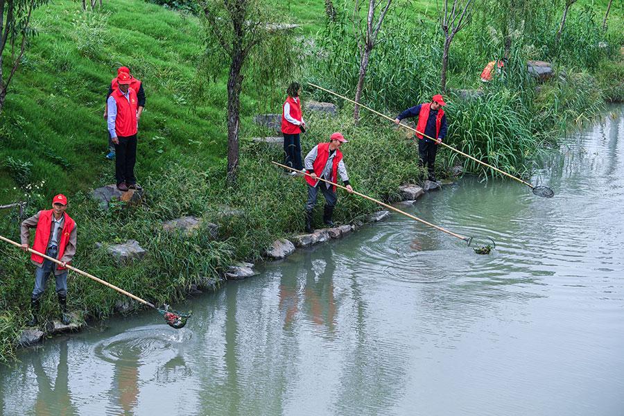 Workers clean a river in Changxing county, Zhejiang province. (Photo/Xinhua)
Key points:

-- Sulfur dioxide and nitrogen oxide emissions will be cut by 3 percent.

-- Achieve a 2-percent drop in both chemical oxygen demand and ammonia nitrogen emissions.