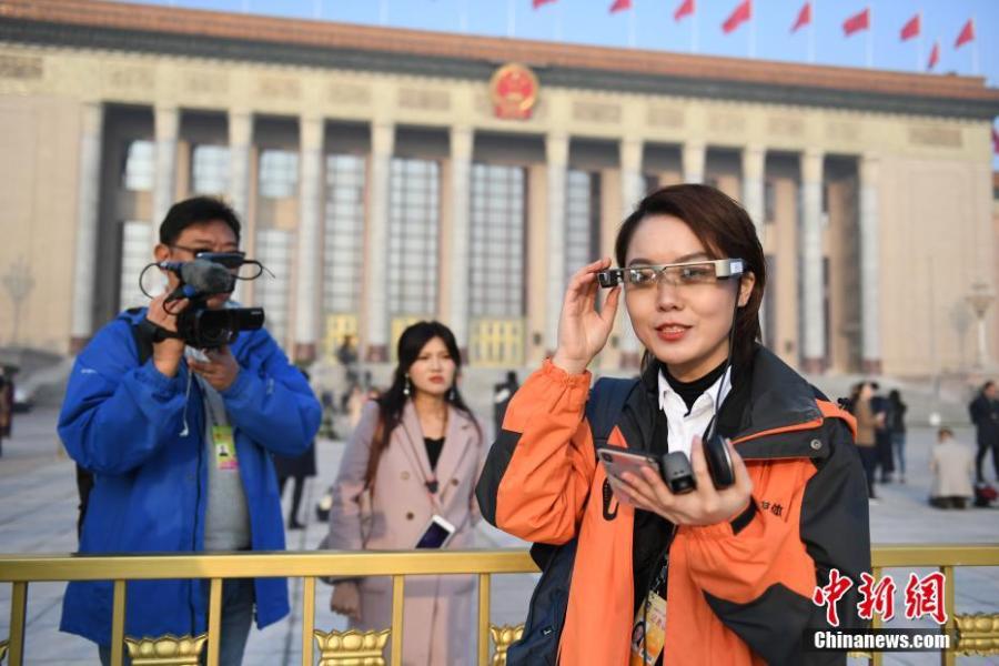 <?php echo strip_tags(addslashes(A reporter wears virtual reality (VR) glasses while covering the second session of the 13th National People's Congress at the Great Hall of the People in Beijing on Tuesday, March 5, 2019. The VR glasses can record the voice of the wearer, and the tiny camera installed on the frame of the glasses can capture high-definition videos. (Photo/China News Service))) ?>