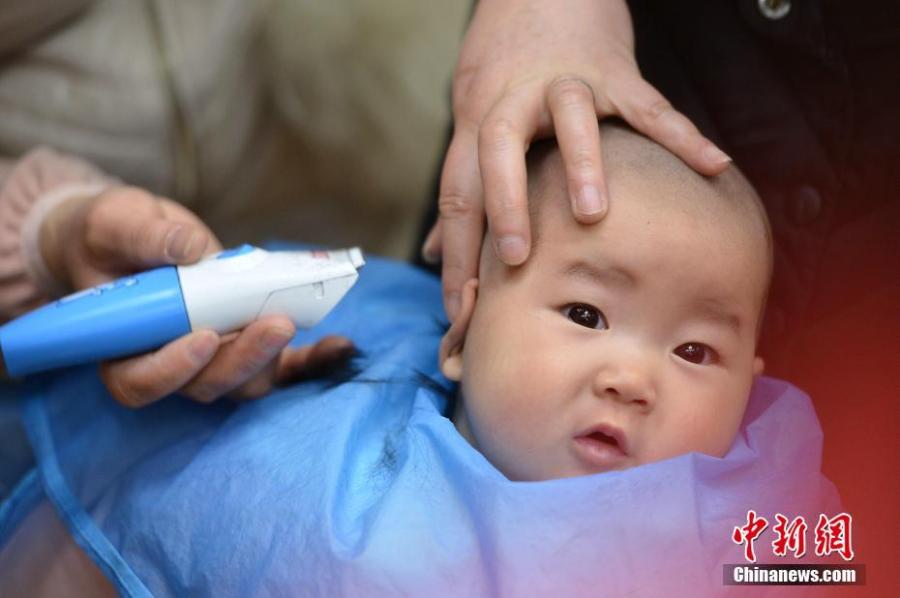 A child gets a haircut at a barbershop in Baokang County, Central China\'s Hubei Province, March 8, 2019. March 8 marks traditional Chinese festival Long Tai Tou (dragon head raising), which refers to the start of spring and farming. During the festival, held on the second day of the second month of the lunar calendar, people play dragon lanterns, eat noodles, shave their hair, and pray for luck.(Photo: China News Service/Yang Tao)