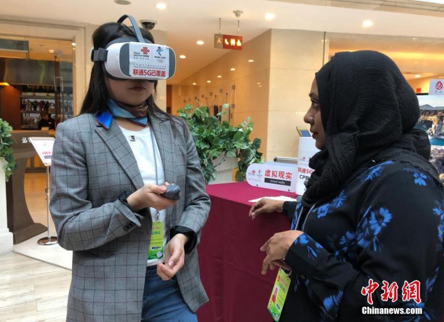 Mongolian journalist Enkhtur Anudari (L) experiences a 5G network device at the media center of the Two Sessions in Beijing\'s Media Center Hotel, March 11, 2019. (Photo: Cui Nan/China News Service)