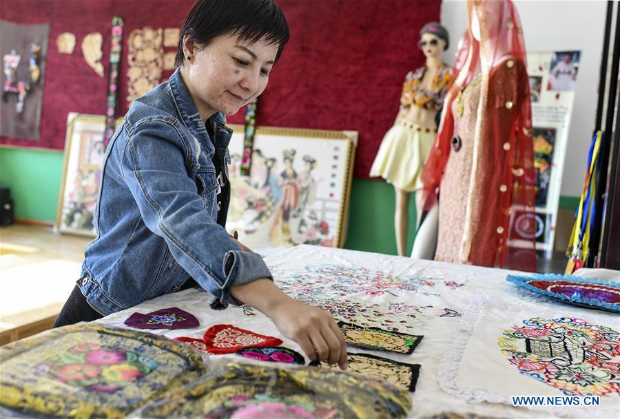 Renagul arranges her embroidery products at her workshop in Yizhou District of Hami City, northwest China\'s Xinjiang Uygur Autonomous Region, on March 8, 2019. The haute couture, literally named \