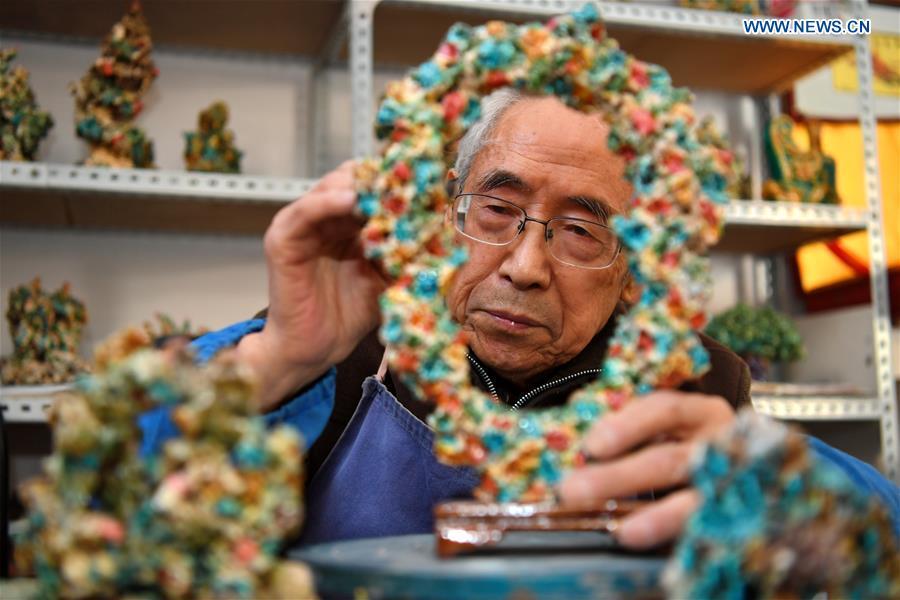 Ge Yuansheng, inheritor of coloured glaze firing skill, a national intangible cultural heritage listed in 2008, works on a piece of coloured glaze made of coal cinder at his workshop in Taiyuan, north China\'s Shanxi Province, March 13, 2019. Ge has been applying his skill of coloured glaze firing to waste coal cinder for five years. After going through dozens of processes, the waste material would be made into delicate artwork. (Xinhua/Cao Yang)