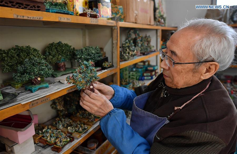Ge Yuansheng, inheritor of coloured glaze firing skill, a national intangible cultural heritage listed in 2008, observes a piece of coloured glaze made of coal cinder at his workshop in Taiyuan, north China\'s Shanxi Province, March 13, 2019. Ge has been applying his skill of coloured glaze firing to waste coal cinder for five years. After going through dozens of processes, the waste material would be made into delicate artwork. (Xinhua/Cao Yang)
