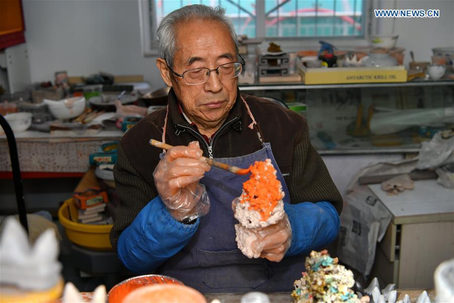 Ge Yuansheng, inheritor of coloured glaze firing skill, a national intangible cultural heritage listed in 2008, works on a piece of coloured glaze made of coal cinder at his workshop in Taiyuan, north China\'s Shanxi Province, March 13, 2019. Ge has been applying his skill of coloured glaze firing to waste coal cinder for five years. After going through dozens of processes, the waste material would be made into delicate artwork. (Xinhua/Cao Yang)
