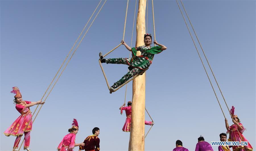 People participate in Shaghydi game in Daolang scenic spot of Awat County, northwest China\'s Xinjiang Uygur Autonomous Region, on March 12, 2019. Shaghydi is an ethnic sport game of Uygur people. Players push the bearings around to help people swing on ropes. (Xinhua/Sadat)