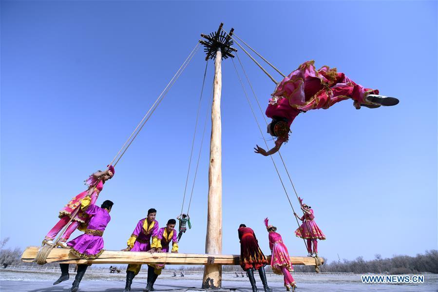 People participate in Shaghydi game in Daolang scenic spot of Awat County, northwest China\'s Xinjiang Uygur Autonomous Region, on March 12, 2019. Shaghydi is an ethnic sport game of Uygur people. Players push the bearings around to help people swing on ropes. (Xinhua/Sadat)