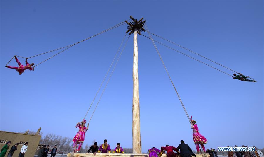 People participate in Shaghydi game in Daolang scenic spot of Awat County, northwest China\'s Xinjiang Uygur Autonomous Region, on March 12, 2019. Shaghydi is an ethnic sport game of Uygur people. Players push the bearings around to help people swing on ropes. (Xinhua/Sadat)