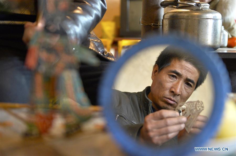 Zhou Zhibing, the apprentice of Pan Mingsheng, carves the shadow puppet at Xinzhai Township of Weiyuan County in Dingxi City, northwest China\'s Gansu province, March 13, 2019. Many local folk artists concentrate on inheriting and passing down the folk art of shadow puppet performing and making in Gansu. They devote themselves to the study of the art and also organize various events to popularize the art. (Xinhua/Li Xiao)