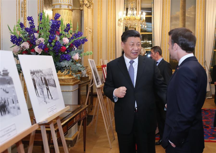 Chinese President Xi Jinping talks with his French counterpart Emmanuel Macron during a photo exhibition marking the 55th anniversary of China-France diplomatic ties and the 100th anniversary of the Chinese Work-Study Movement in France, at the Elysee Palace in Paris, France, March 25, 2019. (Xinhua/Ju Peng)