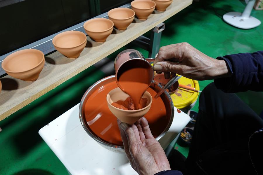 <?php echo strip_tags(addslashes(Wu Lizhu, inheritor of the workmanship of Jianzhan teaware, glazes a piece of porcelain at his workshop in Jianyang District of Nanping City, south China's Fujian Province, March 28, 2019. Jianzhan teaware, a well-known Chinese porcelain originated in Jianyang, dates back to more than 1,000 years ago in Song dynasty (960-1279). It was the best teaware for scholars and literati to use during that time in tea competitions. Jianzhan teawares are known for their variability. Glazes can range in color from dark plum to yellow, green, and blue. During the heating and cooling processes, iron element in the clay can migrate within the glaze to form surface crystals in rich and glossy colors, as in the 