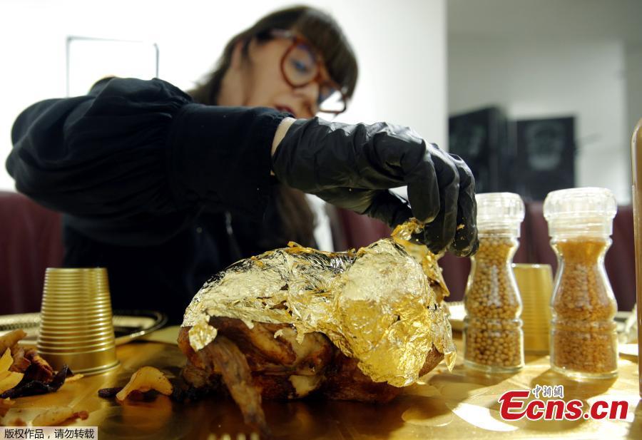 Artist and performer Frederique Lecerf wraps a chicken with a thin sheet of gold as she prepares her performance meal for guests, a golden dinner with decadent 24 carat gold-covered dishes, in Paris, France, March 28, 2019. (Photo/Agencies)