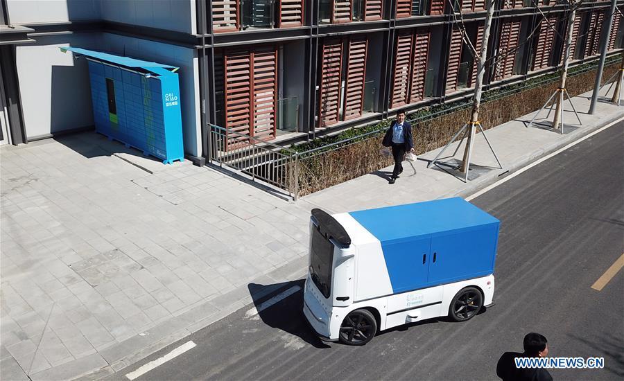 Aerial photo taken on March 31, 2019 shows an unmanned express delivery vehicle running to the intelligent cabinet in Xiongan New Area, north China\'s Hebei Province. The unmanned express delivery vehicle, independently researched and developed by Cainiao Network, Alibaba\'s logistics arm, was recently put into service at Xiongan citizen service center. The new energy vehicle can convey about 200 small packages at one time from delivery station to intelligent cabinet. (Xinhua/Jin Liangkuai)