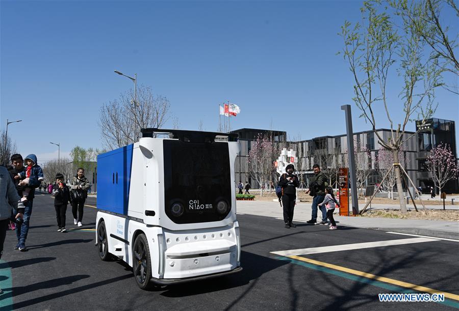 An unmanned express delivery vehicle runs on the street of Xiongan citizen service center in Xiongan New Area, north China\'s Hebei Province on March 31, 2019. The unmanned express delivery vehicle, independently researched and developed by Cainiao Network, Alibaba\'s logistics arm, was recently put into service at Xiongan citizen service center. The new energy vehicle can convey about 200 small packages at one time from delivery station to intelligent cabinet. (Xinhua/Jin Liangkuai)