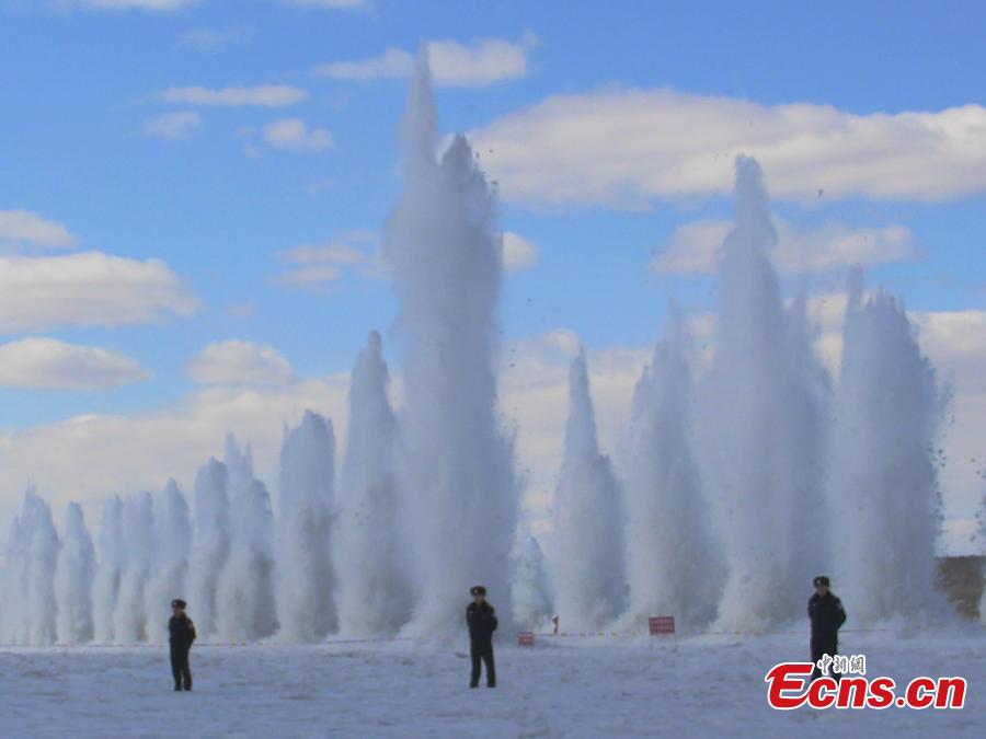 Police officers stand guard as ice is blasted to create safe passage for ships on the still-frozen Tahe section of Heilongjiang River in Northeast China\'s Heilongjiang Province, April 3, 2019. As the weather starts to warm after the extreme cold of winter, local authorities detonate the thick ice to allow vessels to start work again.  (Photo/China News Service)
