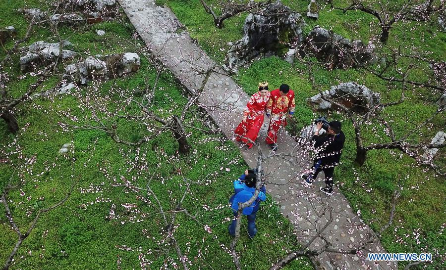 A newly-wed couple view flowers in Wude Town of Shiqian County, southwest China\'s Guizhou Province, April 4, 2019. A group wedding ceremony in traditional style was held here Thursday for couples who have been striving on the frontline for the county\'s fight against poverty. (Xinhua/Yang Wenbin)