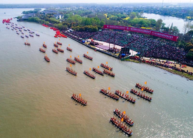 In this aerial photo taken on April 6, 2019, people participate in a boat performance during the 2019 Qintong Boat Festival held at Qinhu National Wetland Park in Jiangyan District of Taizhou, East China\'s Jiangsu province. Hundreds of boats with more than 10,000 boat team members aboard gathered here on Saturday for the Qintong Boat Festival, which has been a centuries-old tradition.