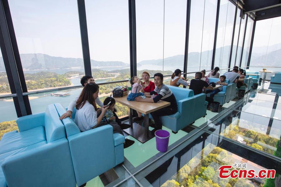 A view of a café inside a glass sightseeing tower, 99 meters above the ground, in Lushan Xihai scenic area in Yongxiu County, East China\'s Jiangxi Province, April 7, 2019. Visitors to the tower can enjoy great views of the mountain and lake. (Photo: China News Service/Zhang Haiyan)