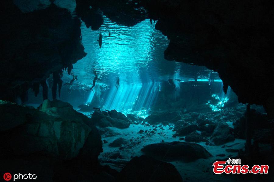 Photo taken by Kirk Zhang shows people diving in freshwater in cenotes illuminated with sunlight from the outside in Mexico. Diving in the caverns, windows to large underground river systems, is a unique experience with  amazing light effects. (Photo/IC)