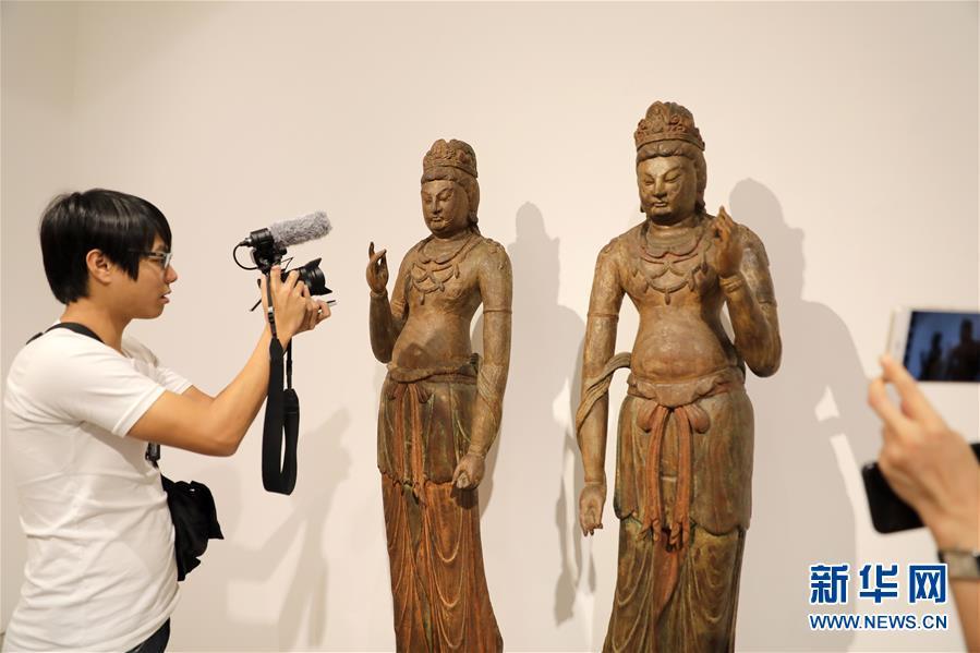 A journalist takes photos of two woodcarving Bodhisattva statues from ancient China\'s Five Dynasties to North Song Dynasty (907-1127) at a media preview of Christie\'s Hong Kong Spring Auctions, April 11, 2019. The estimated price is HK$32 million to HK$45 million ($4-$6 million).  (Photo/Xinhua)