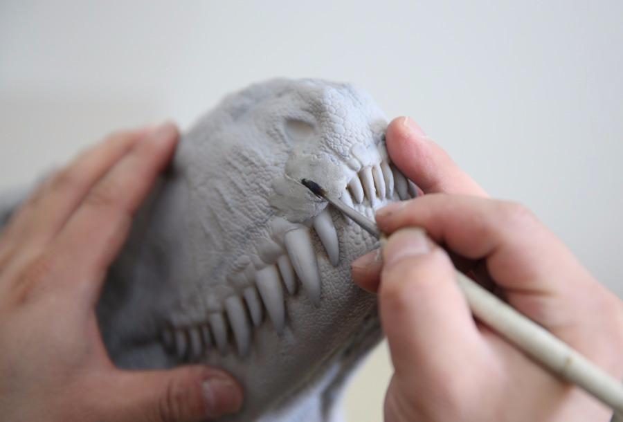 Zhao Chuang carves a dinosaur model. (Photo/China Daily)