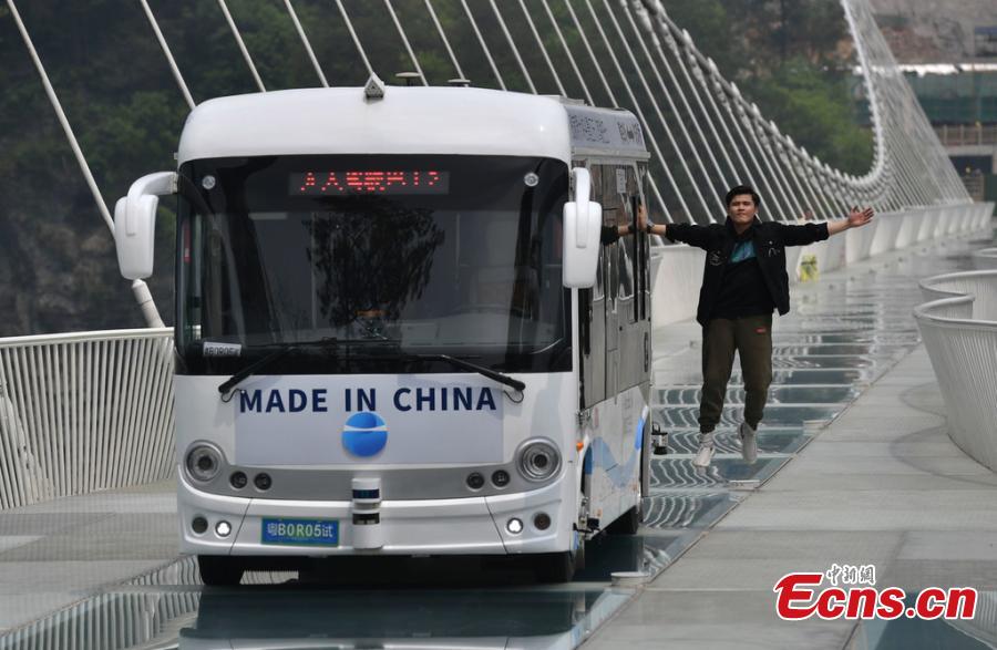 An automated bus drives on the glass bridge of the Grand Canyon scenic area in Zhangjiajie, Hunan Province, on April 24, 2019. The scenic area will offer the self-driving bus service, which can carry 25 people and reach a speed of up to 40 kilometers per hour.  (Photo/IC)