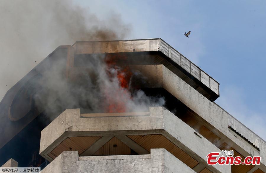 <?php echo strip_tags(addslashes(Fire burns in the top floors of a 21-story Pacific Coastal Plaza condominium in Manila, Philippines, April 29, 2019.  Officials say more than 100 firetrucks converged Monday to battle the blaze that hit the Pacific Coast Plaza condominium in the Paranaque city area of Manila, where one lane of a coastal road along Manila Bay was closed due to falling debris.  A woman died in the accident. (Photo/Agencies))) ?>